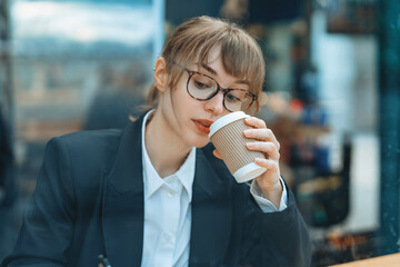 Young professional woman enjoying a coffee break in a modern cafe while deep in thought during a...
