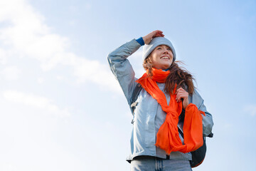Cheerful woman enjoying a sunny day outdoors with a bright scarf in a scenic landscape during late afternoon