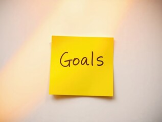 Goals message on sticky post-it note on white background, business planning, sun beams create a natural look