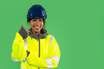 Brightly dressed construction worker smiling and giving a thumbs up in front of a green screen representing safety and positivity in the workplace