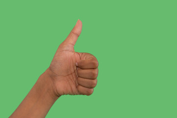 Hand giving a thumbs up gesture against a green background to express positivity and support during...