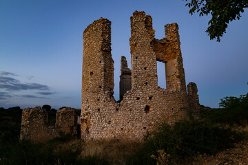 Ruins of an ancient stone structure at dusk surrounded by natural greenery