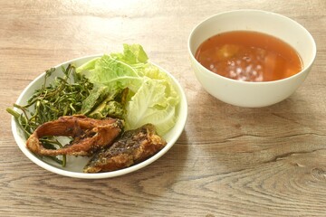 fried snake head fish and egg stuffed climbing wattle in spicy sour soup on plate