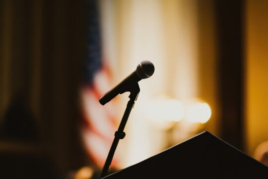 Microphone on Stand with Blurred American Flag in Background.