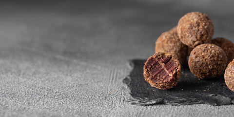 Artisan chocolate truffle candies with berry and fruit filling on dark background, handmade or...