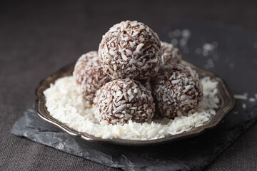 Artisan chocolate coconut truffle candies on dark background from confectionary. Handmade or handcrafted bonbons, chocolatier concept. Horizontal banner, copy space