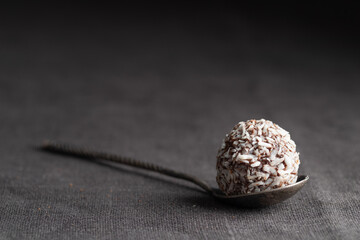 Artisan chocolate coconut truffle candy on dark background from confectionary. Handmade or handcrafted bonbon, chocolatier concept. Horizontal banner, copy space