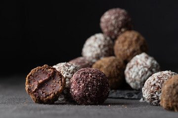 Assortment of gourmet handcrafted vegan chocolate truffle candies on dark background from premium confectionary. Bited handmade bonbon chocolatier concept. Horizontal banner with copy space