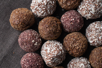 Assortment of gourmet handcrafted vegan chocolate truffle candies on dark background from premium confectionary. Handmade bonbon chocolatier concept. Horizontal banner top view