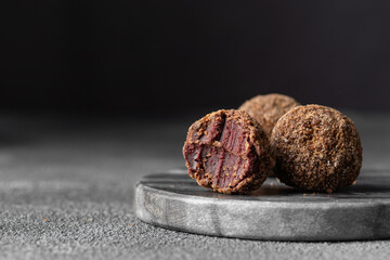 Artisan chocolate truffle candies with berry and fruit filling on dark marble background from confectionary. Handmade or handcrafted bonbons, chocolatier concept. Horizontal banner, copy space