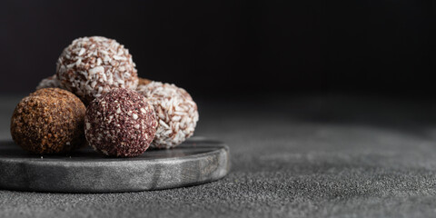 Assortment of gourmet handcrafted vegan chocolate truffle candies on dark marble background from premium confectionary. Handmade bonbons chocolatier concept. Horizontal banner with copy space