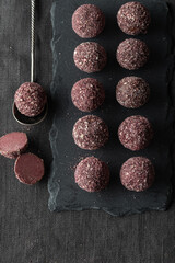 Healthy artisan chocolate truffle candies with berry and fruit filling on dark background from confectionary. Handmade or handcrafted bonbons, chocolatier concept. Vertical banner, copy space