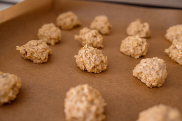 The raw dough, rolled into balls, is laid out on a baking sheet for making oatmeal cookies with nuts. Dietary product, proper nutrition, eco-friendly product, homemade cakes
