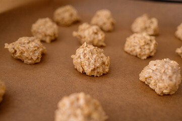 The raw dough, rolled into balls, is laid out on a baking sheet for making oatmeal cookies with nuts. Dietary product, proper nutrition, eco-friendly product, homemade cakes