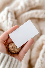 Woman's hand holding blank card on cozy blanket background