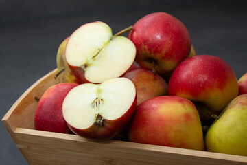 Fresh small organic red apples in a wooden crate on grey table background