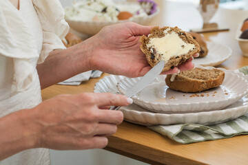 Woman smearing butter on Hot Cross Buns. Happy Easter