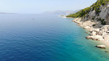 Obraz premium Scenic aerial view of a breathtaking coastal landscape with lush green mountains meeting the turquoise sea. A perfect destination for nature lovers and travel enthusiasts.