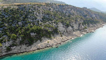 Obraz premium Scenic aerial view of a breathtaking coastal landscape with lush green mountains meeting the turquoise sea. A perfect destination for nature lovers and travel enthusiasts.