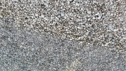 Minimalist aerial composition of a rocky shore where dry and wet pebbles meet. The diagonal split adds depth and texture, suitable for backgrounds, web design, and editorial use.