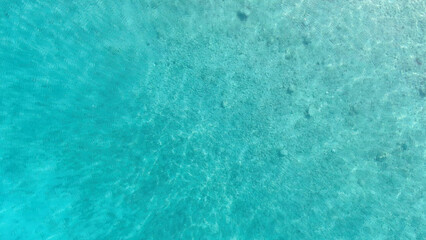 A mesmerizing aerial shot of crystal-clear turquoise waters, revealing the underwater textures beneath. Perfect for backgrounds, nature themes, and travel-related designs.