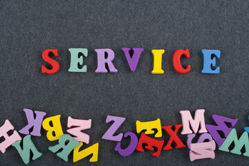 SERVICE word on black board background composed from colorful abc alphabet block wooden letters, copy space for ad text. Learning english concept.
