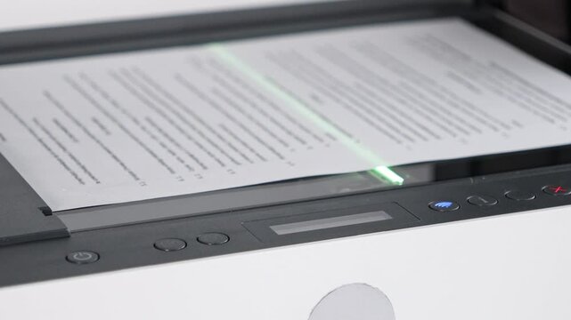 document being scanned on flatbed printer with visible green light and digital control panel in modern home office setup