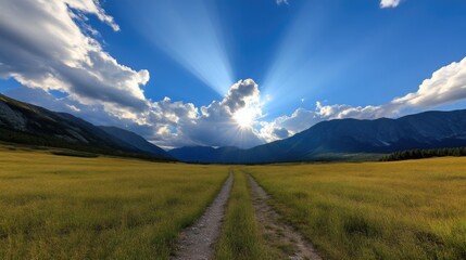 Sunbeams illuminating a pathway through a golden meadow, framed by mountains and clouds