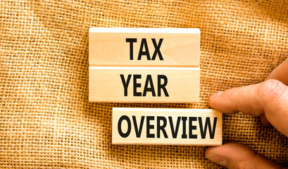 Tax year overview symbol. Concept words Tax year overview on beautiful wooden blocks. Beautiful canvas background. Businessman hand. Business tax year overview concept. Copy space.