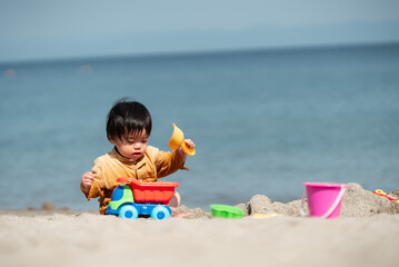 海で砂遊びする1歳の男の子
