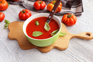 Fresh, healthy tomato soup with basil, tomatoes  on wooden background. Spanish gazpacho soup.