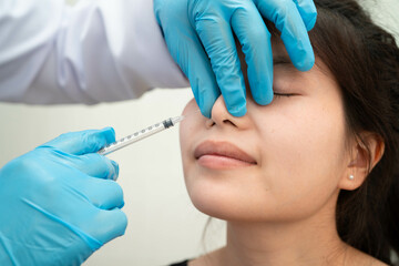 Asian woman receiving plastic surgery shape of nose performed on face.