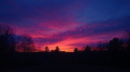 Fototapeta premium Wind turbines silhouetted against a colorful evening sky