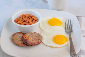 fried eggs with sausage patty  and baked beans