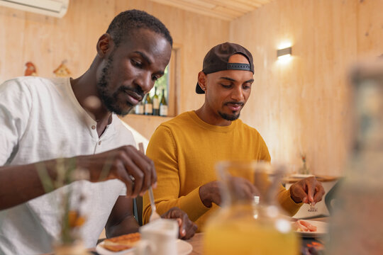 Two African American LGBT couple having breakfast, tasting fresh fruit and vegetables, enjoying delicious healthy food taste in a hotel accommodation. - Powered by Adobe