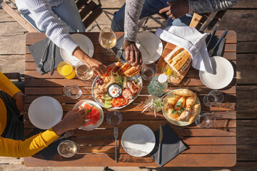 Friends enjoying their vacation, eating lunch outdoor terrace of a glamping resort surrounded by...