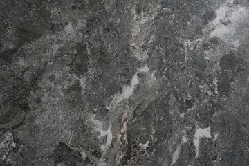 a close-up view of a textured, dark gray stone surface with natural veining and mineral patterns