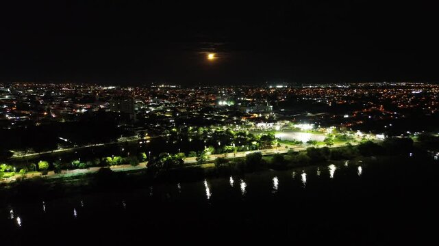 Cidade em noite de lua cheia beira rio