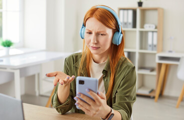 Woman reacts with sadness to bad news while working or learning online from home. Using a phone,...