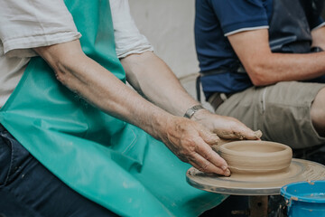 cropped image of male craftsman working on potters wheel at pottery studio