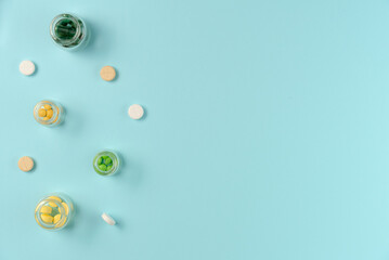 Tablets in glass jars on blue background. Flat lay, top view. Copy space