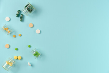 Tablets in glass jars on blue background. Flat lay, top view. Copy space