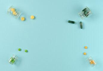 Frame of tablets in glass jars on blue background. Flat lay, top view. Copy space