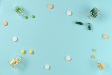 Frame of tablets in glass jars on blue background. Flat lay, top view. Copy space