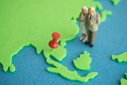 Old senior couple person standing looking at destination country on map for retirement abroad. Planning to retire abroad, expat retirement overseas, cost of living, financial planning concept.