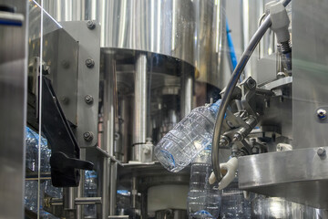 The  empty drinking water bottles  hanging on the conveyor belt for filling process.