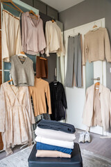 Stacked pile of clothing prepared for resale, donation, or recycling, with wardrobe with outfits in...