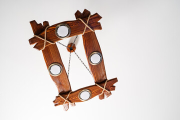 A wooden chandelier with plastic electric lamps and rope decoration, hanging from the white...