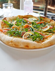 Pizza with salmon, Philadelphia cheese and arugula on white table top view.