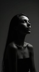 Woman with long hair is standing in front of a wall. The image has a moody and mysterious feel to it, as the woman's face is the only visible part of her body
